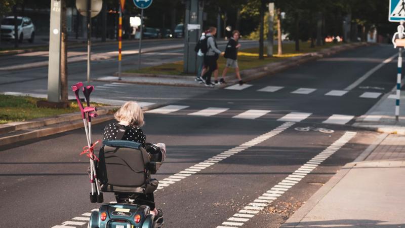 Elderly woman riding a mobility scooter on a road