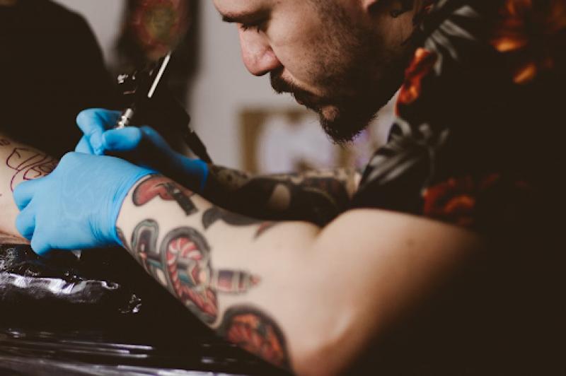 A tattoo artist using a tattoo gun